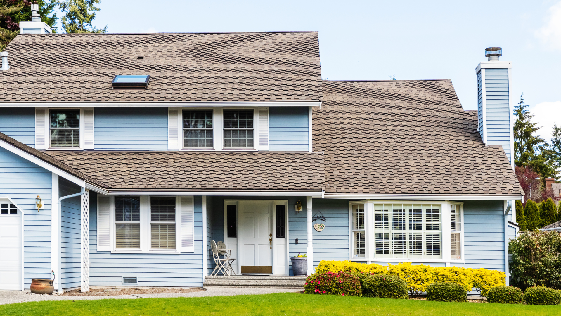 Blue two-story house with white shuttered windows and white front door.